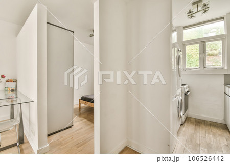 a bathroom with white walls and wood flooring the room is well lit by natural light from the large window 106526442