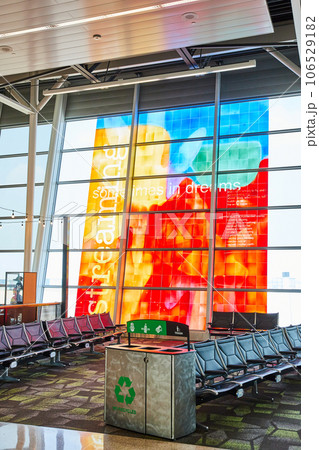Metal recycling receptacle with empty airport terminal chairs and vibrant window art Metal recycling receptacle with empty airport terminal chairs and vibrant window art 106529182