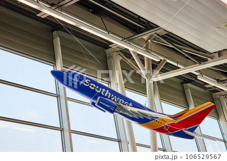 Southwest airplane model hanging from white ceiling beams with windows and white sky day 106529567