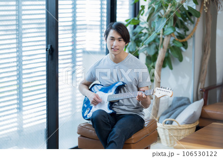 自宅でギターの練習をする若い男性 自宅でギターの練習をする若い男性 106530122