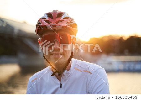 Man is wearing protective helmet, sunglasses and sportswear during evening ride in city. 106530469