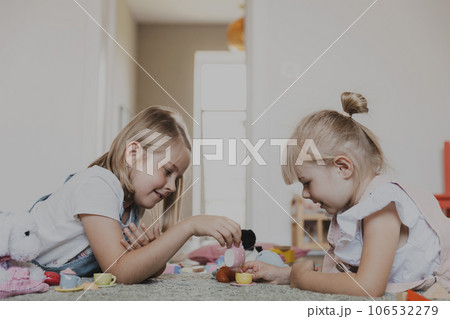 Close-up of female children playing with colorful toy play tea set. Kids lying at home bedroom or kindergarten, nursery. Educational eco-friendly game for child. Development of logical thinking Close-up of female children playing with colorful toy play tea set. Kids lying at home bedroom or kindergarten, nursery. Educational eco-friendly game for child. Development of logical thinking 106532279