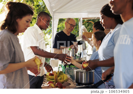 Diverse group of female volunteers donate free food to the poor and homeless people. Voluntary ladies offer refreshment and aid to those in need supporting a food drive for a non-profit organization. Diverse group of female volunteers donate free food to the poor and homeless people. Voluntary ladies offer refreshment and aid to those in need supporting a food drive for a non-profit organization. 106534905