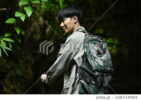 Male hiker with backpack and trekking sticks exploring nature in green forest. Travel, adventure and active life concept 106534969