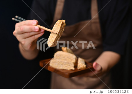 Man holding Tempeh with bamboo chopsticks Vegan appetizers, traditional Indonesian soy product 106535128