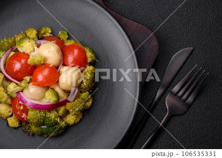 Delicious fresh salad with broccoli, cherry tomatoes, mushrooms, onions, salt, spices and herbs 106535331