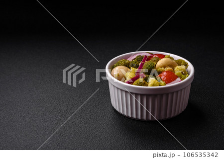 Delicious fresh salad with broccoli, cherry tomatoes, mushrooms, onions, salt, spices and herbs 106535342