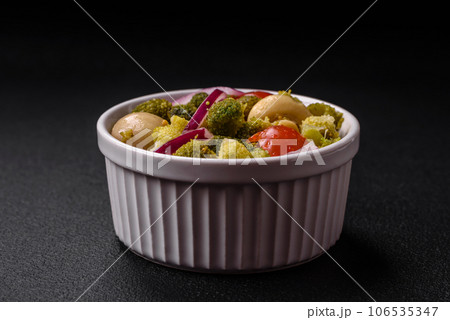 Delicious fresh salad with broccoli, cherry tomatoes, mushrooms, onions, salt, spices and herbs 106535347