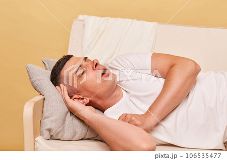 Day napping. Weekend sofa drowsiness. Funny man resting lying on couch at home keeps mouth open, being tired and exhausted. 106535477