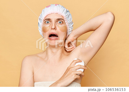 Shocked scared woman holding epilator isolated on beige background making epilation of armpit looking at camera skin care and hygiene feeling fear to use tool for a first time. Shocked scared woman holding epilator isolated on beige background making epilation of armpit looking at camera skin care and hygiene feeling fear to use tool for a first time. 106536153
