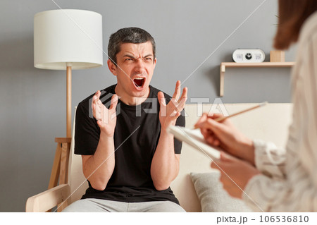 Young Caucasian man at consultation in psychologist office, feeling angry and mad, screaming frustrated and furious, shouting with anger, rage and aggression. Young Caucasian man at consultation in psychologist office, feeling angry and mad, screaming frustrated and furious, shouting with anger, rage and aggression. 106536810