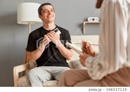 Satisfied delighted smiling man in casual T-shirt sitting at psychologist office and talking with specialist enjoying therapy session, having grateful expression. Satisfied delighted smiling man in casual T-shirt sitting at psychologist office and talking with specialist enjoying therapy session, having grateful expression. 106537119