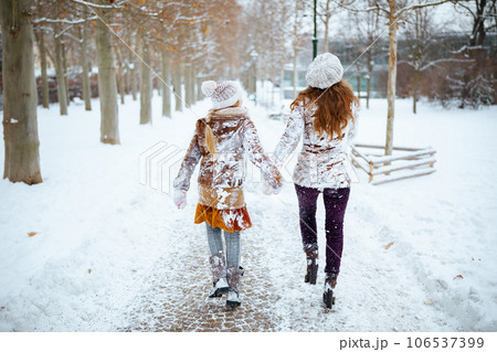 mother and child in coat, hat, scarf and mittens walking 106537399
