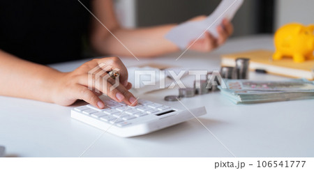 businesswomen is keeping a record of his income and expenses, he plans his finances by using his monthly savings to buy funds to make it grow faster. Concept of saving money for investment 106541777