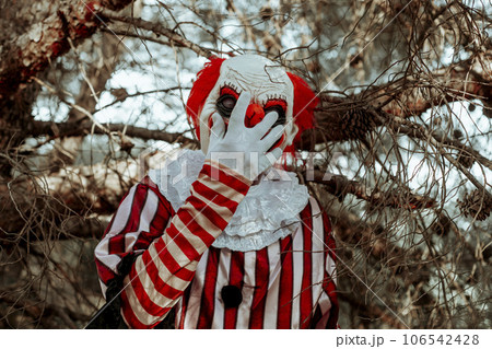 man putting on a clown mask in the woods man putting on a clown mask in the woods 106542428