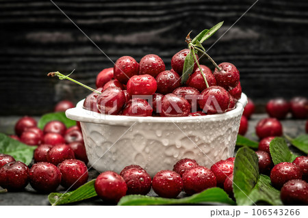 Fresh sweet cherries bowl with leaves on wooden desktop table. water drops on Fresh sour cherry berries Fresh sweet cherries bowl with leaves on wooden desktop table. water drops on Fresh sour cherry berries 106543266