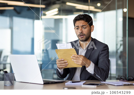 Upset and disappointed with the results of the achievement, young businessman received a mail message, hispanic man desperately reads the news, man works inside the office with a laptop. 106543299