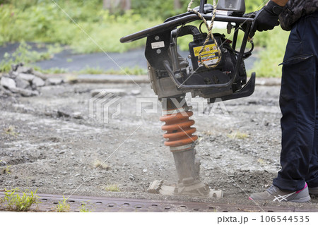 タンピングランマーで地面をならす作業員男性 転圧作業の写真素材