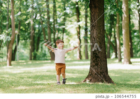 Little Caucasian boy playing outdoors in the park with a stick from a tree Little Caucasian boy playing outdoors in the park with a stick from a tree 106544755