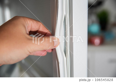 Torn and damaged sealing gum on the refrigerator door. Replacing the old sealing rubber with a new one 106545828