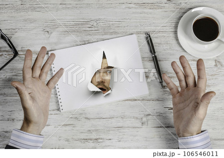 Male face through the hole in paper 106546011
