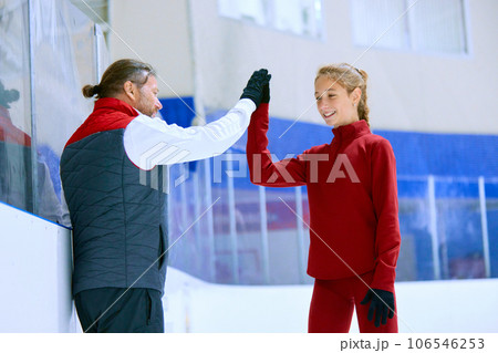 Success. Figure skating trainer, coach cheering his student, girl, giving high five. Ice rink arena background 106546253