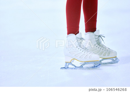 Close-up cropped image of female legs in red leggings and white skates on ice skate arena. Training and skating. Close-up cropped image of female legs in red leggings and white skates on ice skate arena. Training and skating. 106546268