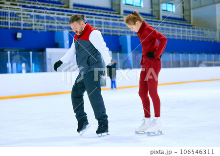 Professional skater, man training girl, learning figure skating activity on ice rink arena. Sport lessons with coach 106546311