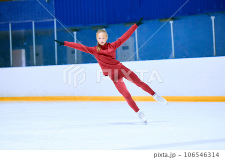 Concentration and motivation. Teen girl in red sportswear, figure skating athlete in motion on ice rink arena, training Concentration and motivation. Teen girl in red sportswear, figure skating athlete in motion on ice rink arena, training 106546314