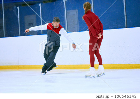 Professional skater, man training girl, learning figure skating activity on ice rink arena. Sport lessons with coach 106546345