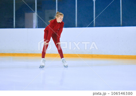 Girl in red sportswear, figure skating athlete standing on ice rink area and preparing for training session 106546380
