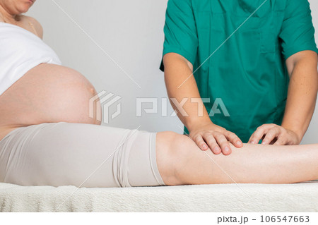 Doctor masseur makes a foot massage to a pregnant girl from pain in the joints of the legs and varicose veins. Relieve fatigue and pain. Doctor masseur makes a foot massage to a pregnant girl from pain in the joints of the legs and varicose veins. Relieve fatigue and pain. 106547663