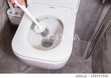 Modern silicone brush for cleaning the dirt of the wall-mounted toilet. Toilet care and hygiene concept, close-up 106547698
