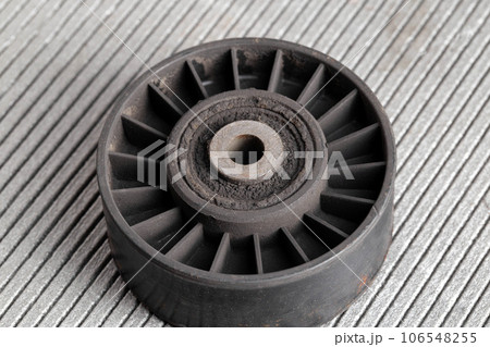Old dirty car roller made of plastic and bearing on a gray background. Close-up Old dirty car roller made of plastic and bearing on a gray background. Close-up 106548255