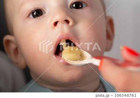 The first feeding with fruit puree for a baby boy who is 6 months old, close-up The first feeding with fruit puree for a baby boy who is 6 months old, close-up 106548761