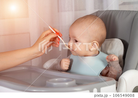 Mother feeds baby boy vegetable puree from a spoon. Feeding children 7 months. Close-up. Copy space for text Mother feeds baby boy vegetable puree from a spoon. Feeding children 7 months. Close-up. Copy space for text 106549008