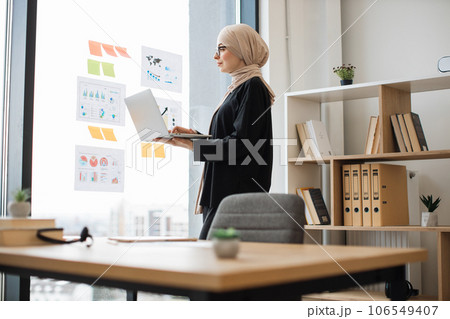 Manager typing on laptop near graphic materials on window 106549407
