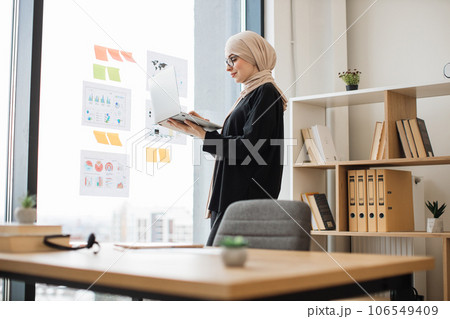 Manager typing on laptop near graphic materials on window 106549409