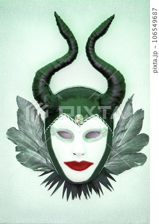 Abstract theatrical mask with horns and feathers on a green background. Abstract theatrical mask with horns and feathers on a green background. 106549687