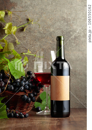 Glass and bottle of red wine with blue grapes and vine branches. Glass and bottle of red wine with blue grapes and vine branches. 106550162