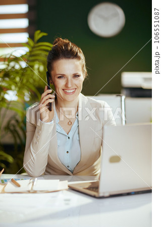 happy business owner woman in green office talking on phone 106551087