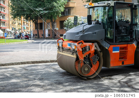 Orange Tractor with cylinder for asphalt paving on road 106551745