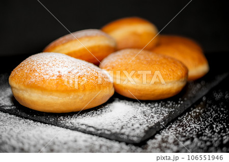 German Krapfen with drizzling glazed sprinkles in black elegant background 106551946