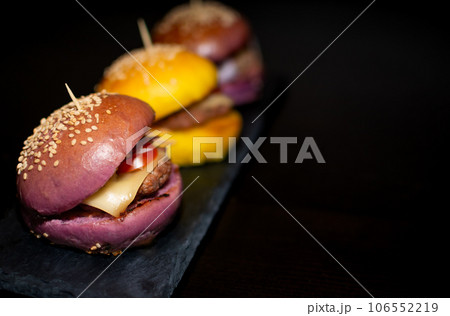 Colored Mini Gourmet Burgers with sesame seeds on black slate board 106552219