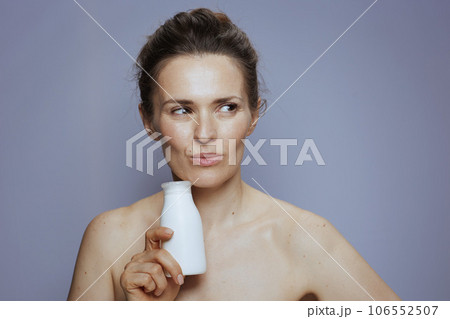 pensive young woman with cosmetic cream jar 106552507
