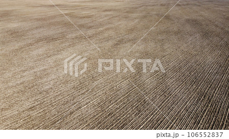 An aerial perspective unveils a plowed farm field with the backdrop of rich black soil. 106552837