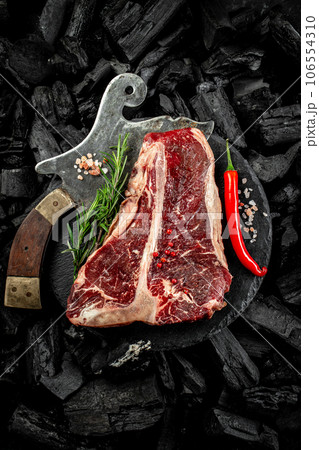 marbled beef T-bone or porterhouse beef meat Steak on BBQ grill coal. Fresh meat for grilling. steak raw striploin of beef. top view. place for text 106554310