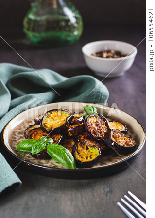 Appetizing fried eggplant with spices and herbs on a plate on the table vertical view 106554621