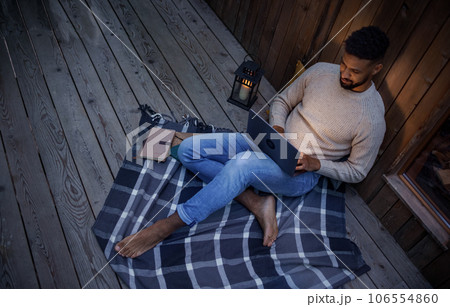 Happy young man with laptop resting outdoors in a tree house, weekend away and remote office concept. 106554860