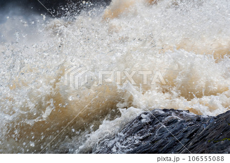 muddy turbulent stream under a rock during high water 106555088